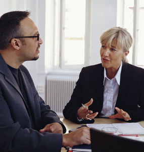 Kvinna och man samtalar i ett mötesrum.