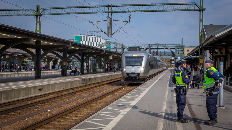 Tåg inkommer till Lunds centralstation med två poliser i förgrunden.