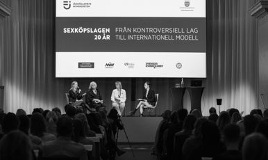 En publik vänd mot en panel på en scen. I bakgrunden står det "Sexköpslagen 20 år - från kontroversiell lag till internationell modell" projicerat på en stor duk