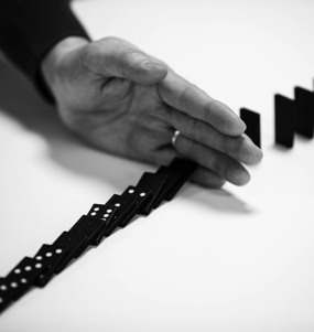 Hand som stoppar dominobrickor från att falla