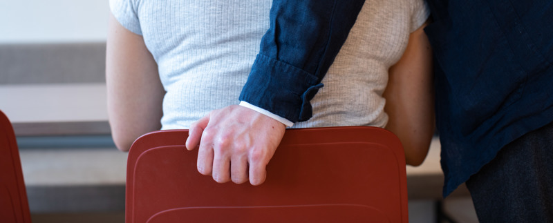 Man lägger sin hand på stolen som en kvinna sitter i
